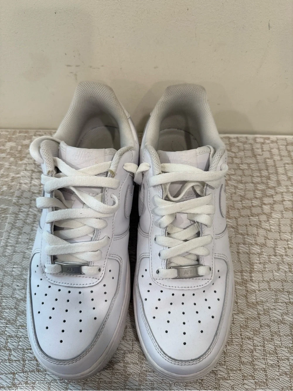 These are iconic Nike Air Force 1 sneakers in an all-white colorway.
